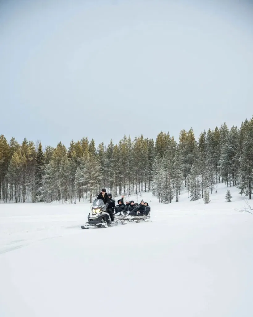 Schneemobil bringt Gruppe von Gästen auf den See. Schneemobiltour