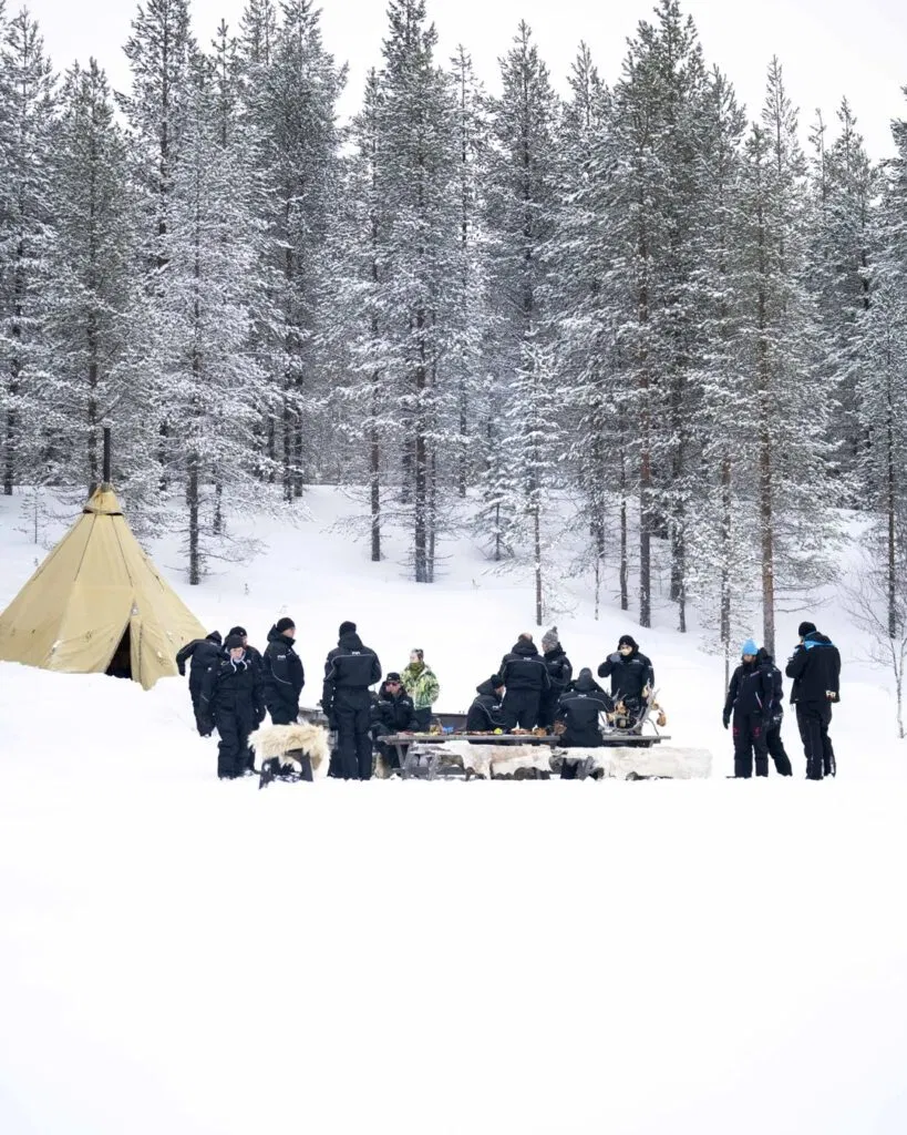 Gruppe von Menschen beim Eisangeln auf dem See mit einem Tippi.