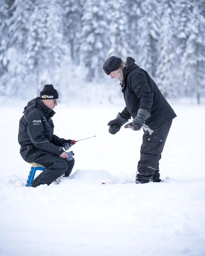 Zwei Männer angeln im Winter auf einem See.