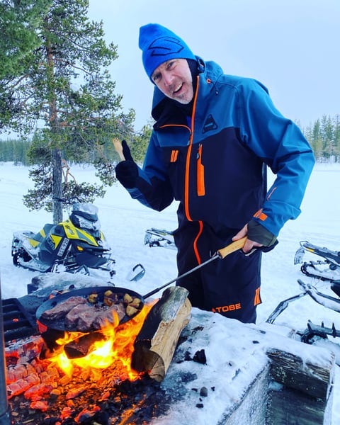 Guide einer Schneemobil Skidoo bei grillen des Mittagessens auf dem Lagerfeuer.